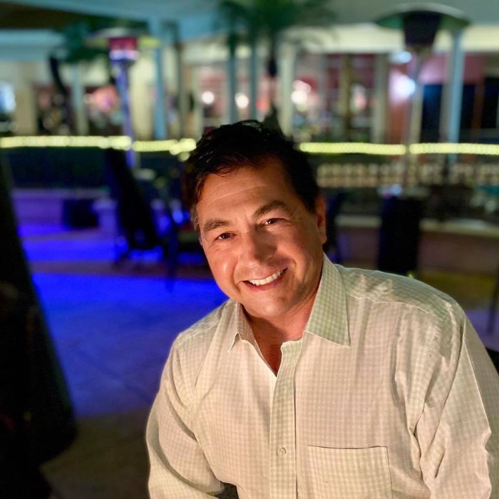 Smiling, Seated, Dark Haired Man Wearing A White Button Down Shirt Smiling, Seated, Dark Haired Man Wearing A White Button Down Shirt